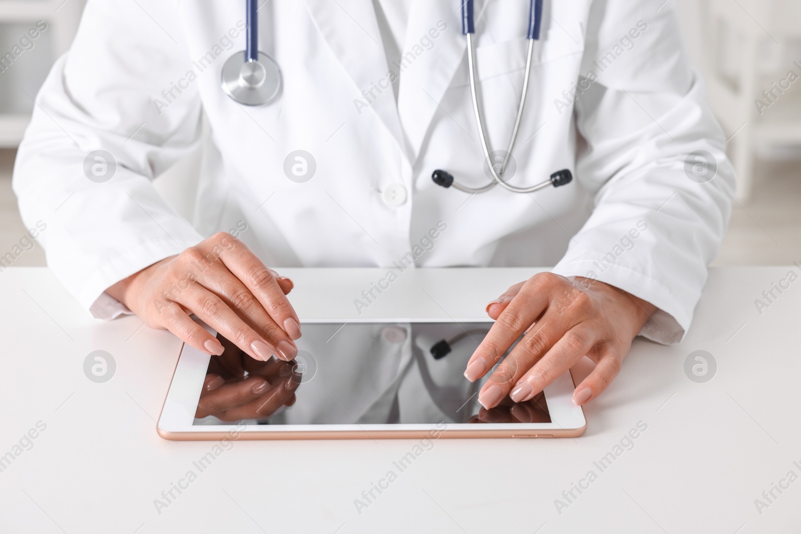 Photo of Doctor with tablet at table in clinic, closeup view