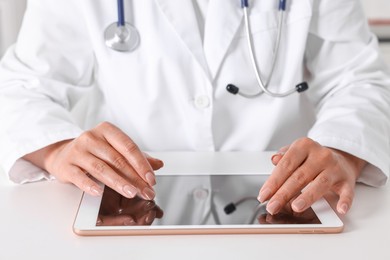 Photo of Doctor with tablet at table in clinic, closeup view