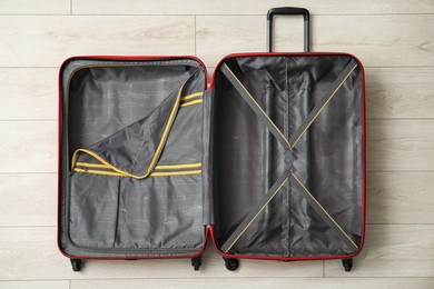 Photo of Open empty suitcase for travelling on floor indoors, top view