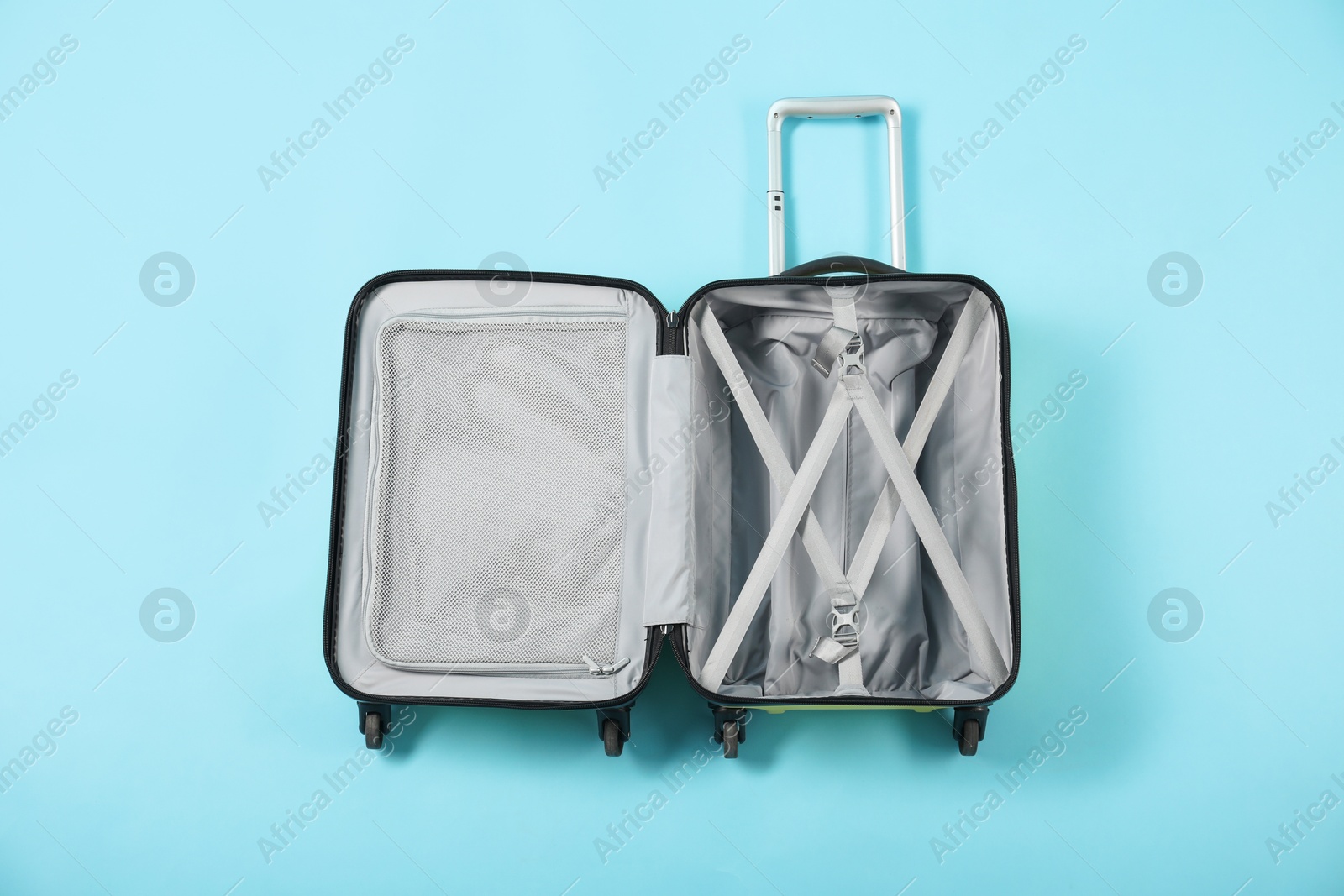 Photo of Open empty suitcase for travelling on light blue background, top view