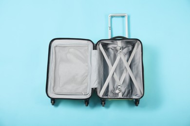 Photo of Open empty suitcase for travelling on light blue background, top view