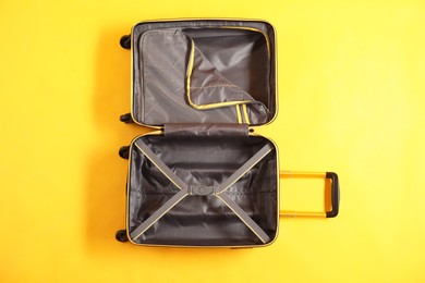 Photo of Open empty suitcase for travelling on yellow background, top view