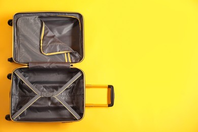 Photo of Open empty suitcase on yellow background, top view. Space for text