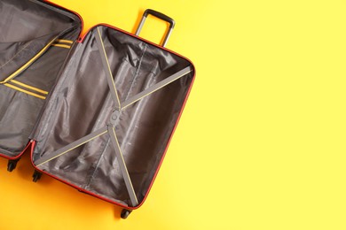 Photo of Open empty suitcase on yellow background, top view. Space for text