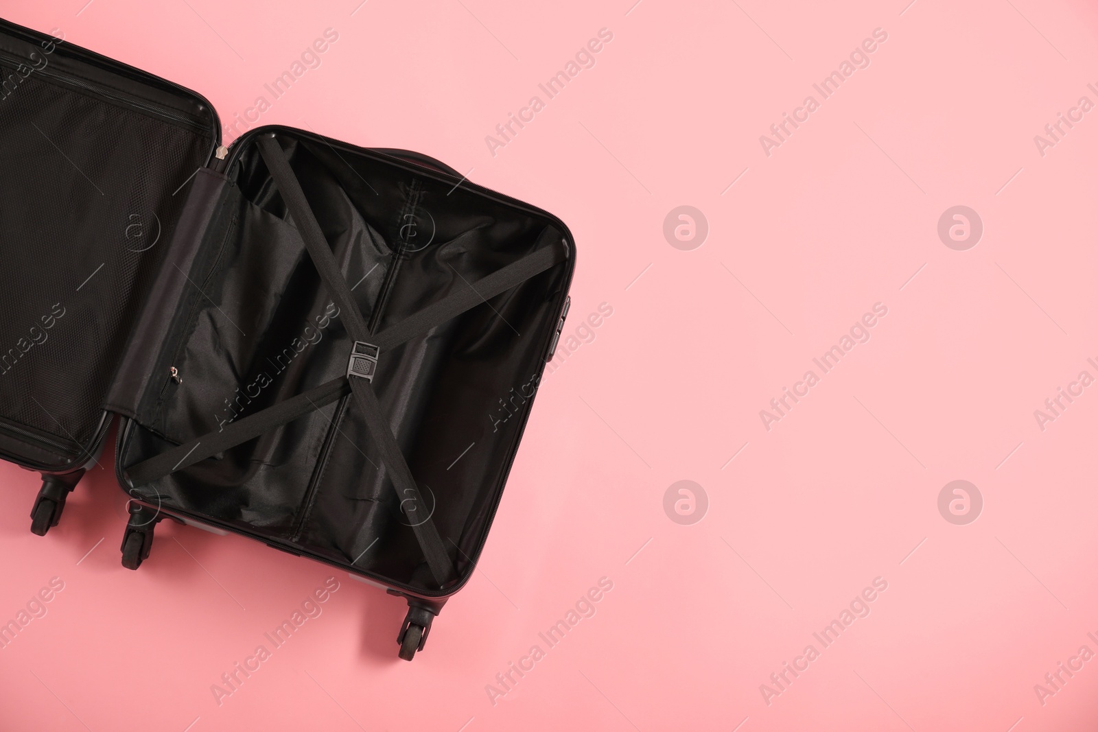 Photo of Open empty suitcase on pink background, top view. Space for text