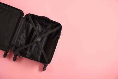 Photo of Open empty suitcase on pink background, top view. Space for text