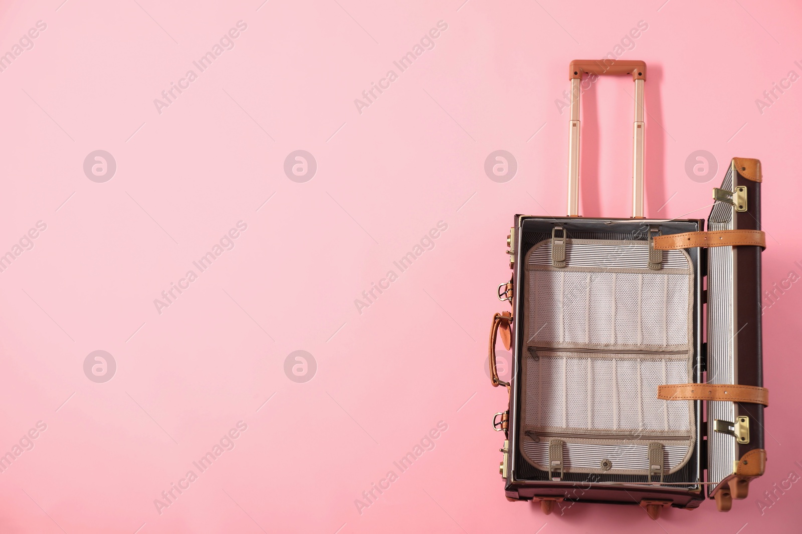 Photo of Open empty suitcase on pink background, top view. Space for text