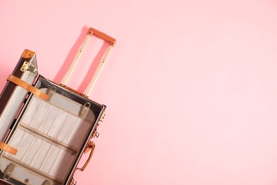 Photo of Open empty suitcase on pink background, top view. Space for text