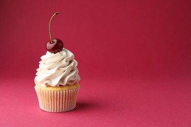 Photo of Delicious cupcake with cream and cherry on red background, space for text