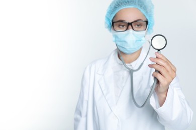 Doctor holding stethoscope on white background, selective focus. Space for text