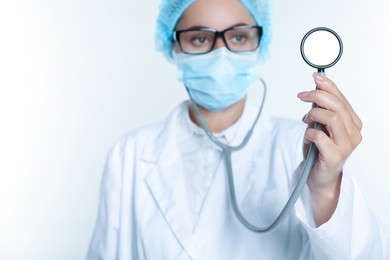 Photo of Doctor holding stethoscope on white background, selective focus