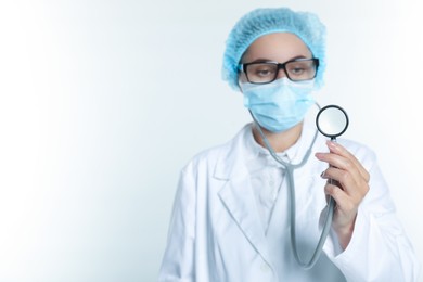 Doctor holding stethoscope on white background, selective focus. Space for text