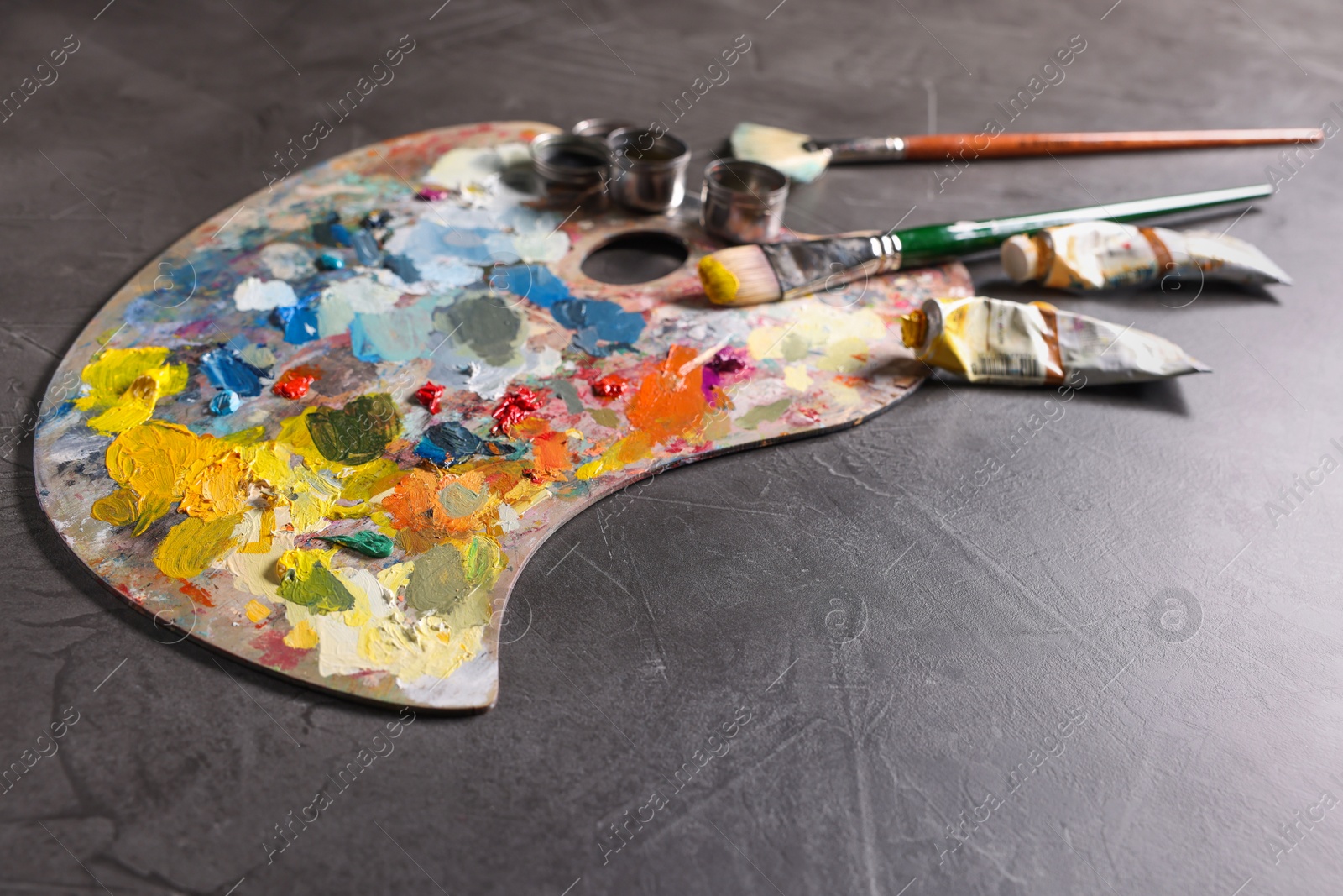 Photo of Artist's palette, brushes and paints on grey table, space for text