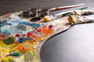 Photo of Artist's palette, brushes and paints on grey table, closeup. Space for text