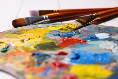 Artist's palette, brushes, paints on table, closeup