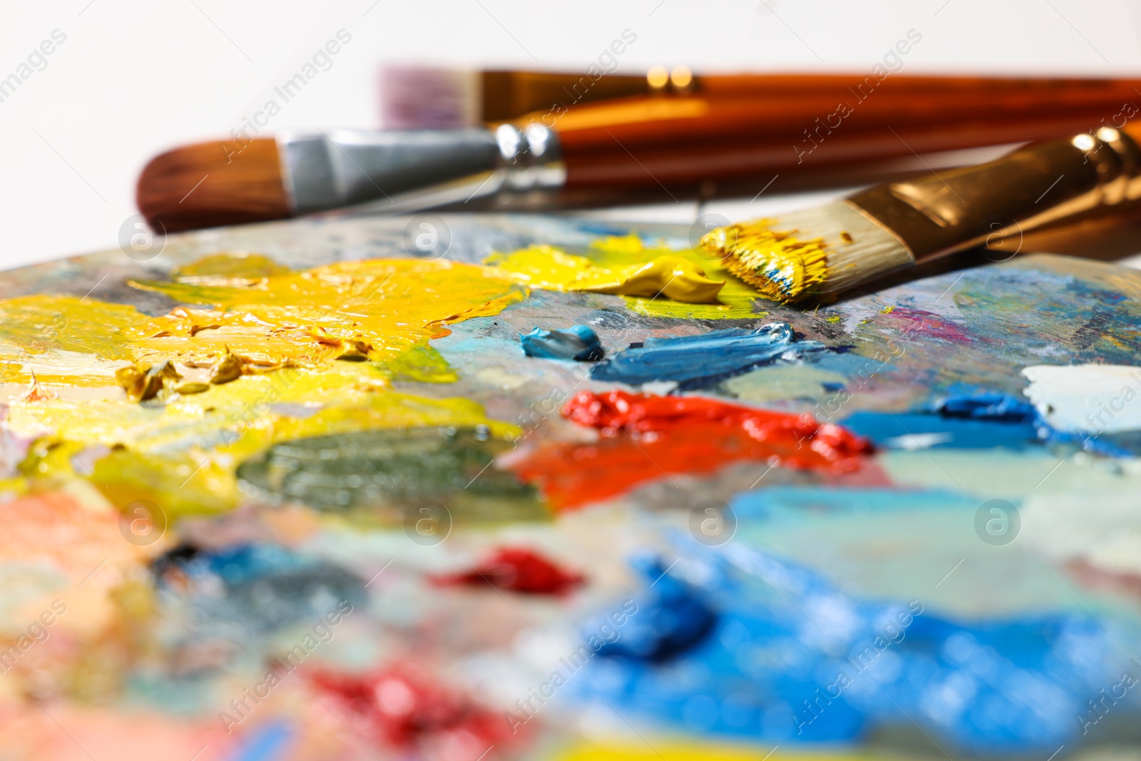 Photo of Artist's palette, brushes, paints on table, closeup