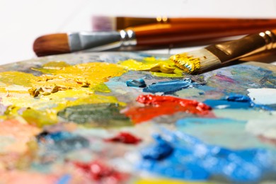 Artist's palette, brushes, paints on table, closeup