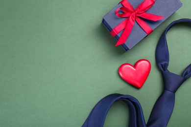 Photo of Happy Father's Day. Heart, gift box and tie on green background, flat lay. Space for text