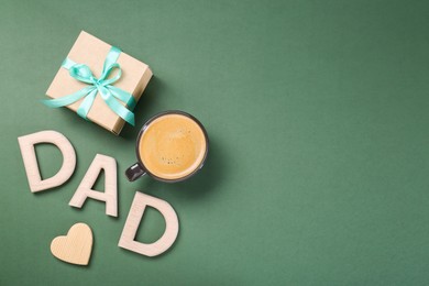 Happy Father's Day. Word Dad made with wooden letters, cup of coffee, gift box and heart on green background, flat lay. Space for text