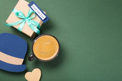 Photo of Happy Father's Day. Paper hat, cup of coffee, gift box and heart on green background, flat lay. Space for text