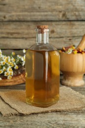 Photo of Tincture in bottle and medicinal herbs on wooden table