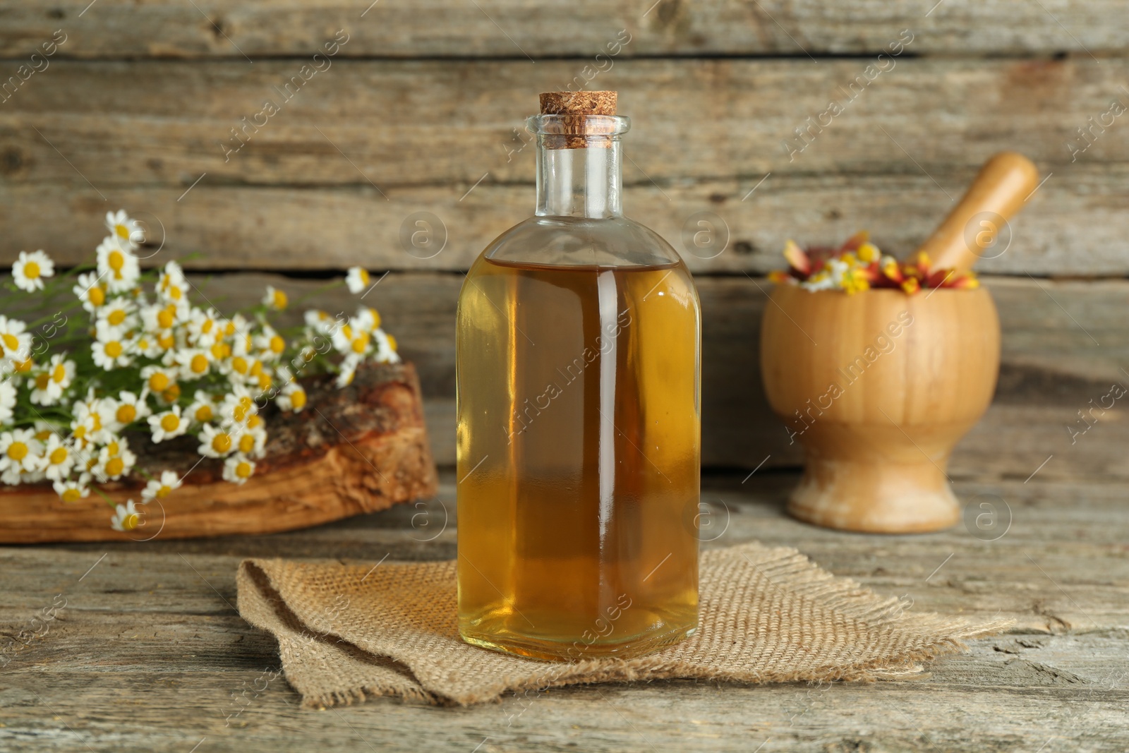 Photo of Tincture in bottle, medicinal herbs and mortar with pestle on wooden table