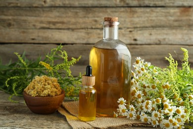 Photo of Tinctures in bottles and medicinal herbs on wooden table