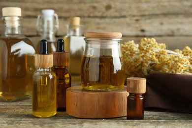 Photo of Different tinctures and helichrysum flowers on wooden table