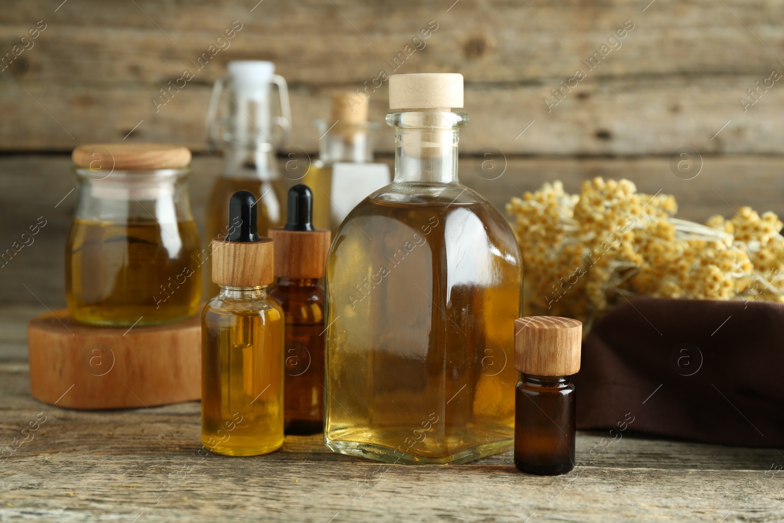 Photo of Different tinctures and helichrysum flowers on wooden table