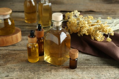 Photo of Different tinctures and helichrysum flowers on wooden table