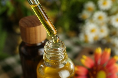 Photo of Dripping tincture from pipette into bottle on blurred background, closeup