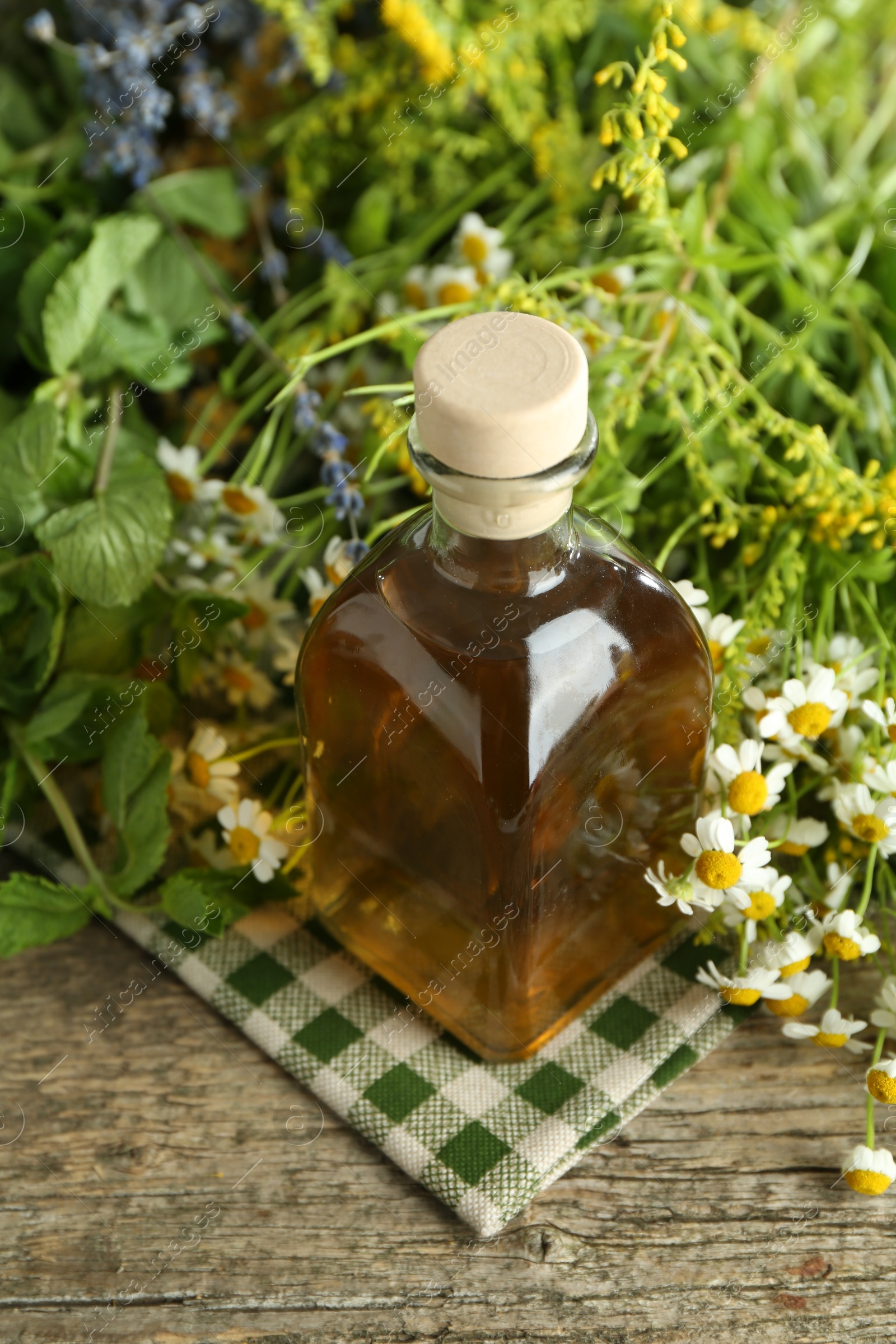 Photo of Tinctures in bottle and medicinal herbs on wooden table