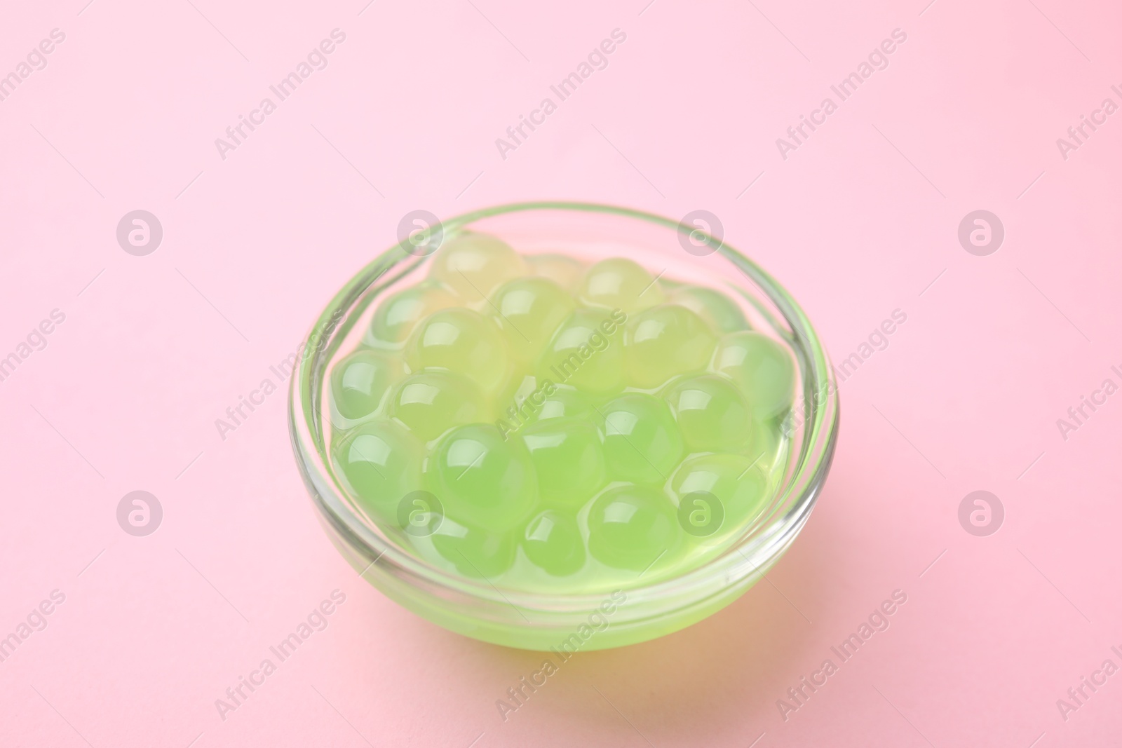 Photo of Bright tapioca pearls in bowl on pink background, closeup