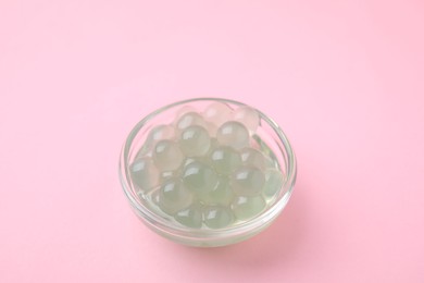 Photo of Tapioca pearls in bowl on pink background, closeup