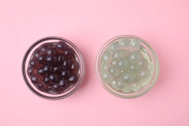 Photo of Color tapioca pearls in bowls on pink background, flat lay