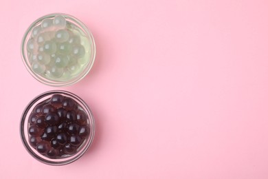 Photo of Color tapioca pearls in bowls on pink background, flat lay. Space for text