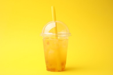 Tasty bubble tea in plastic cup on yellow background