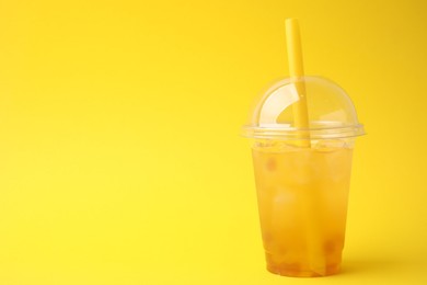 Tasty bubble tea in plastic cup on yellow background, space for text