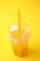 Photo of Tasty bubble tea in plastic cup on yellow background, closeup