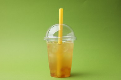 Tasty bubble tea in plastic cup on green background