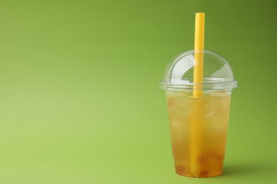 Tasty bubble tea in plastic cup on green background, space for text