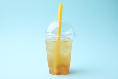 Tasty bubble tea in plastic cup on light blue background