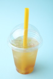 Tasty bubble tea in plastic cup on light blue background, closeup