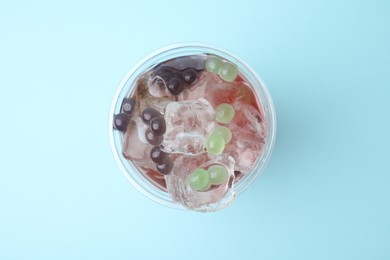 Tasty bubble tea in plastic cup on light blue background, top view