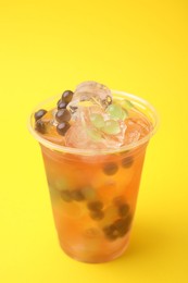 Tasty bubble tea in plastic cup on yellow background