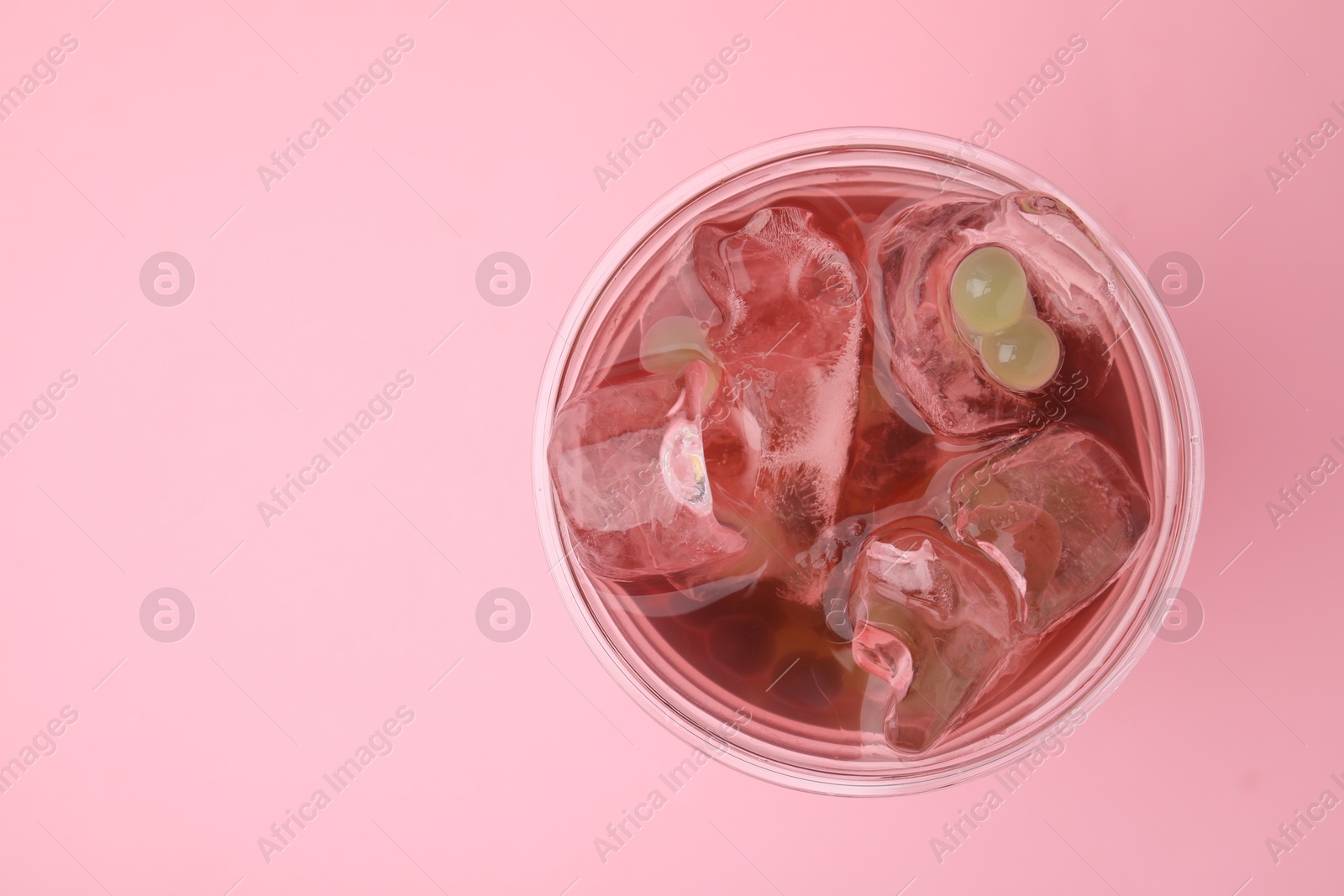 Photo of Tasty bubble tea in plastic cup on pink background, top view. Space for text