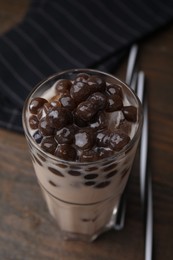 Photo of Tasty milk bubble tea in glass on wooden table, closeup