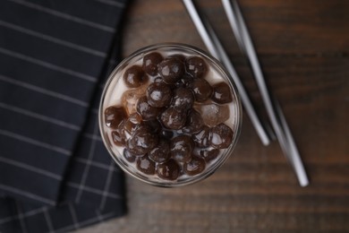 Photo of Tasty milk bubble tea in glass and straws on wooden table, flat lay