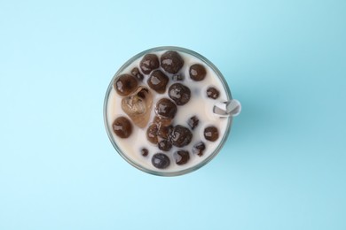 Photo of Tasty milk bubble tea in glass on light blue background, top view