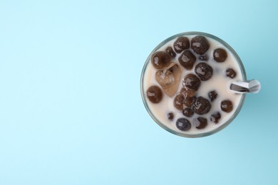 Photo of Tasty milk bubble tea in glass on light blue background, top view. Space for text